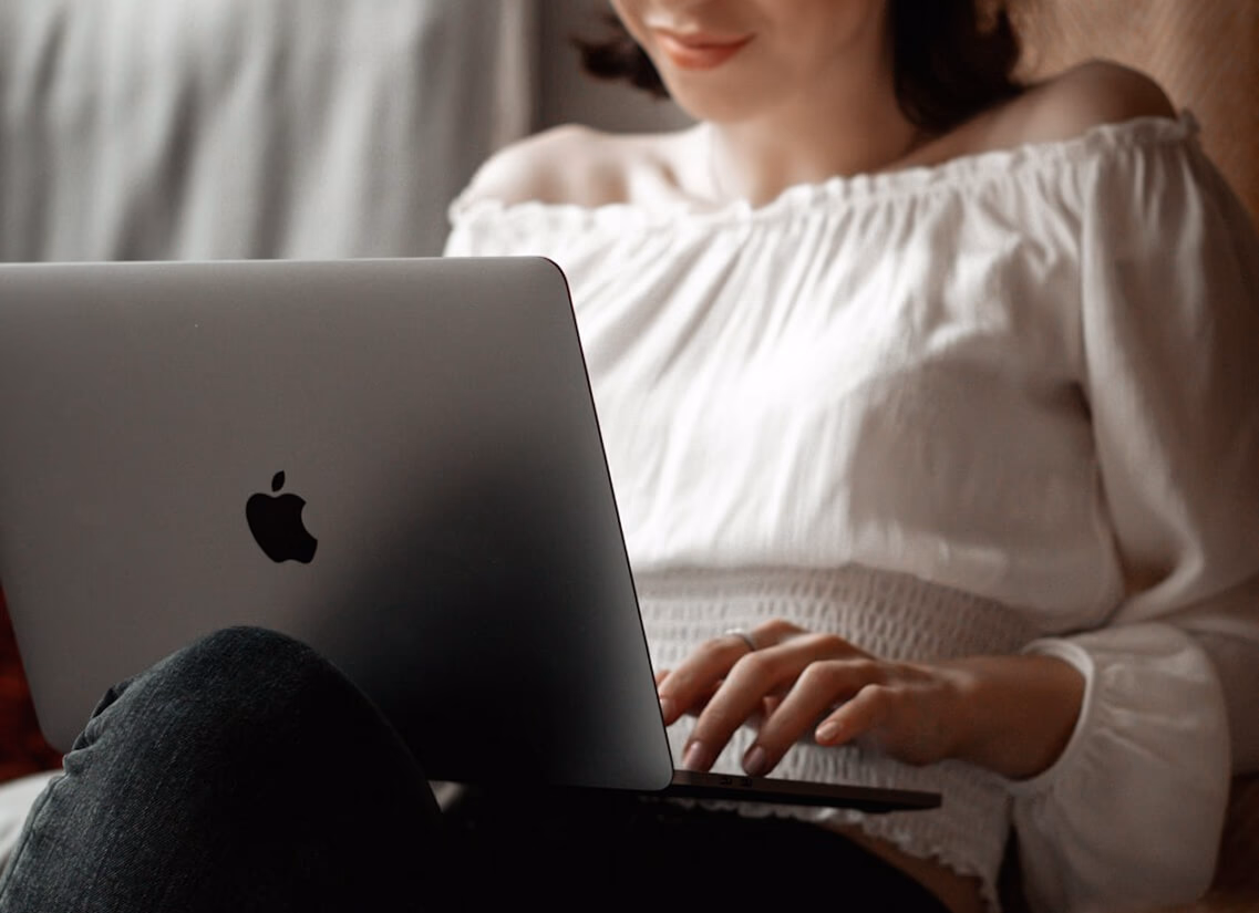 Person in a white off-shoulder top using a MacBook laptop, with text overlay 'What's new in digital?' and the BrandHive Socials logo in the top corner.